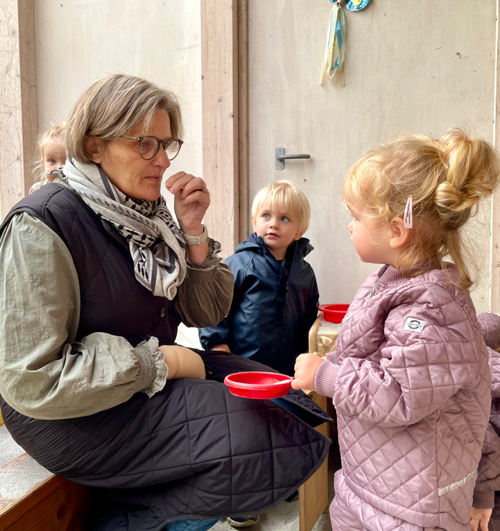 Voksen sidder med tre børn udenfor