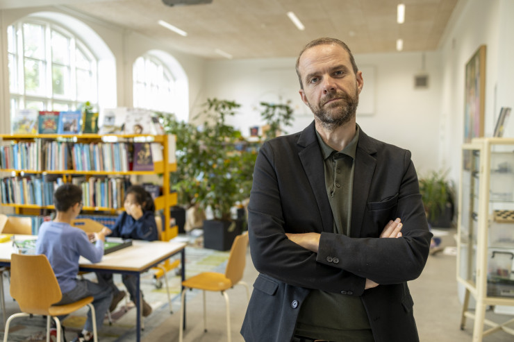 Thomas Medom med armene over kors på et skolebibliotek