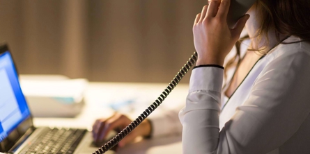 Person med bærbar pc taler i telefon