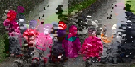 Børn i regntøj ser på dyr