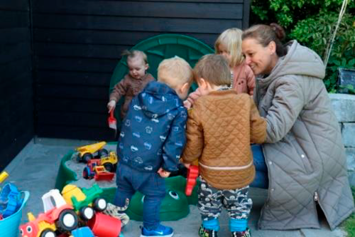 En voksen og fire børn leger udenfor