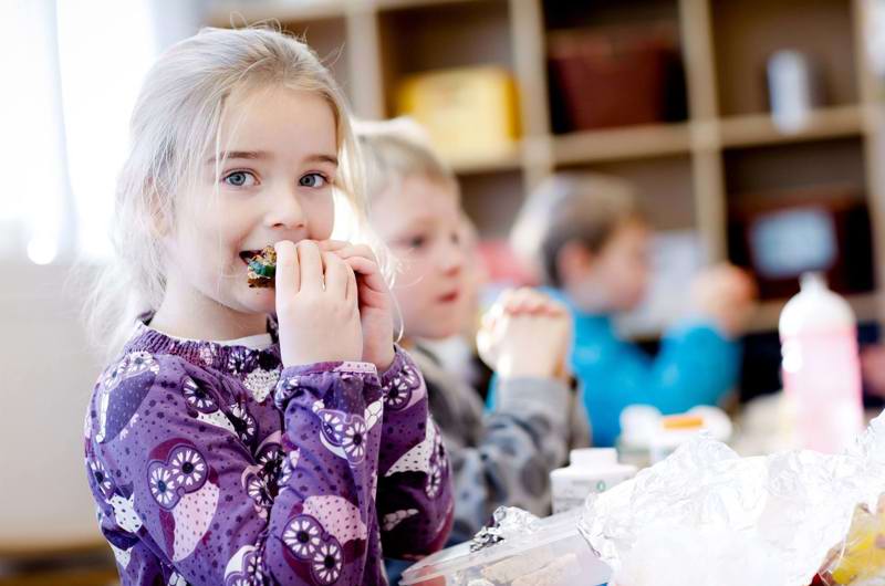 En pige spiser sin madpakke i klassen
