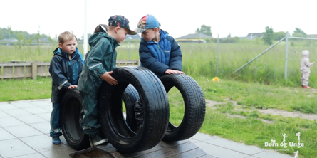 Tre børn i regntøj med store bildæk