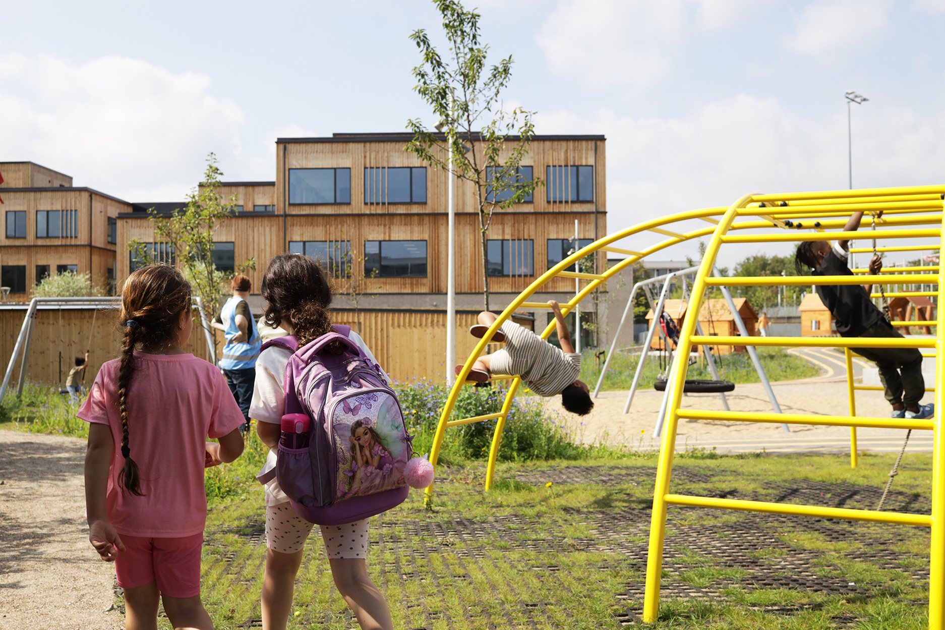 To piger udenfor Kløverskolen ved et legestativ