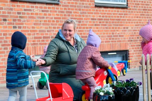 En voksen og fire børn leger udenfor